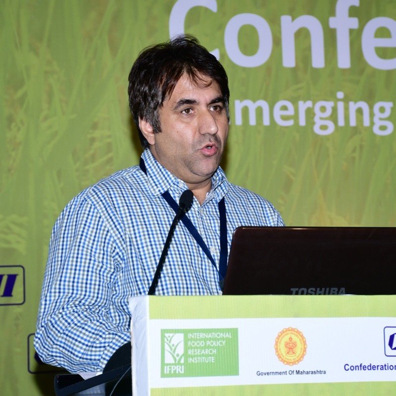 Dr. Manzoor Hussain Dar speaking at a conference, presenting his work on agricultural innovations and seed systems at ICRISAT.