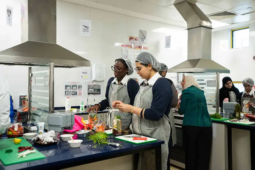 Students participating in a food preservation workshop, actively engaging in hands-on cooking activities in a classroom kitchen setting.