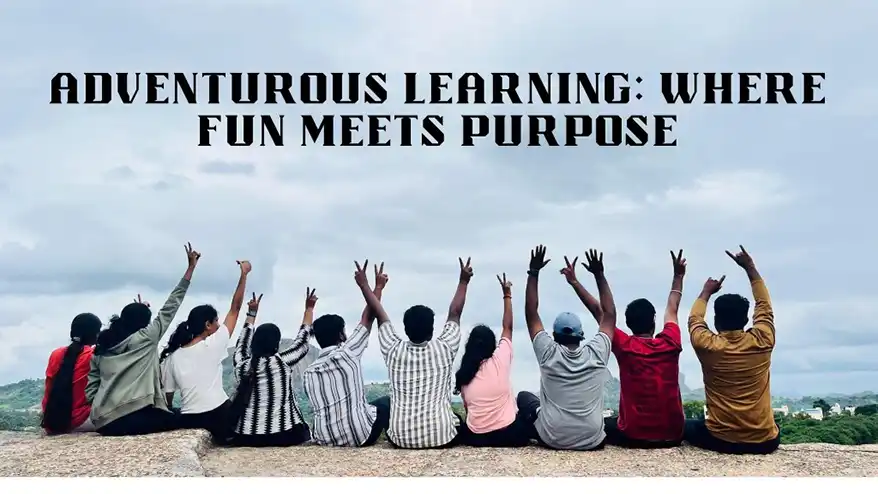 A group of individuals sitting on a rocky ledge, facing away from the camera, with their arms raised in celebration. The background features a scenic landscape under a cloudy sky with the text 'ADVENTUROUS LEARNING: WHERE FUN MEETS PURPOSE' displayed prominently.