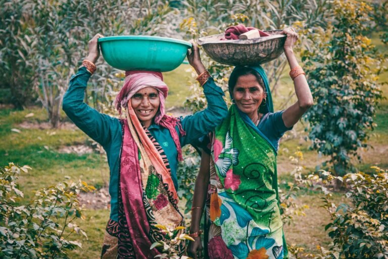 two women wearing traditional dress carrying basins