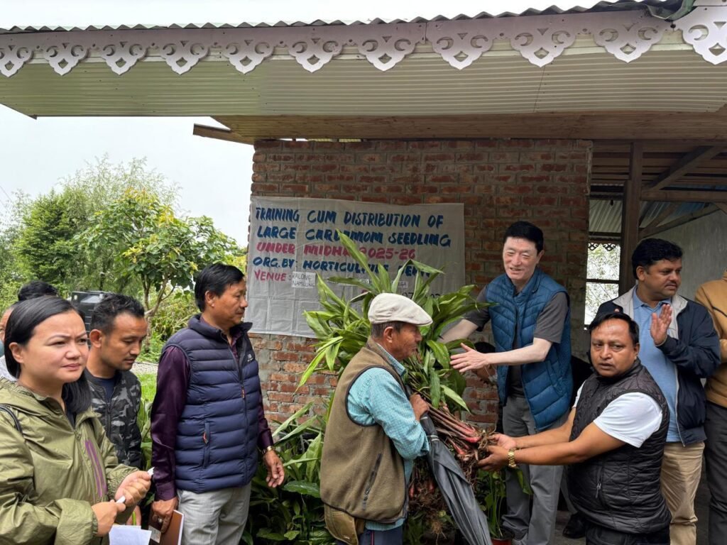 A group of individuals at a training event in Sikkim, engaged in the distribution of large cardamom seedlings, with participants receiving seedlings and discussing agricultural practices.