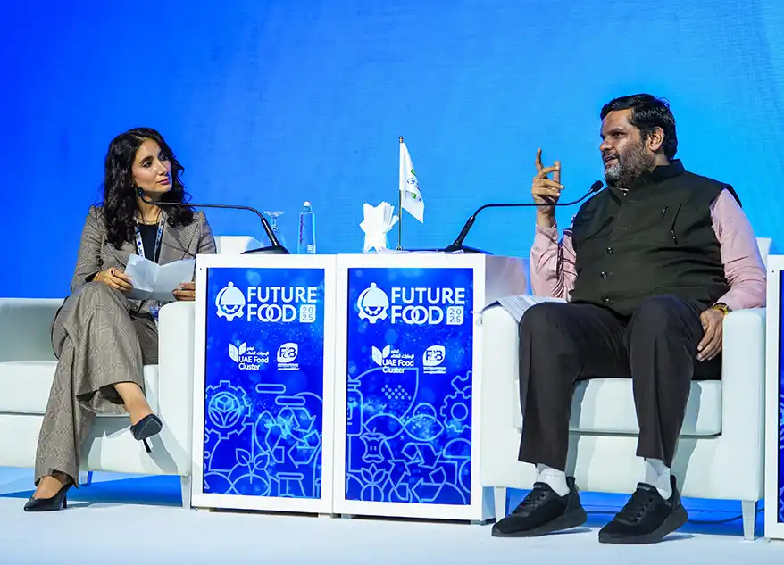Prof. (Dr.) Gourav Vallabh and a female interviewer engaged in a discussion at the Future Food Forum, with a blue backdrop and event branding.