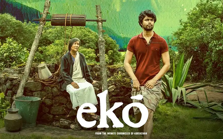 A scene from the film 'ekõ', featuring a man and an elderly woman sitting by a stone structure in a lush green landscape, with a colorful background.