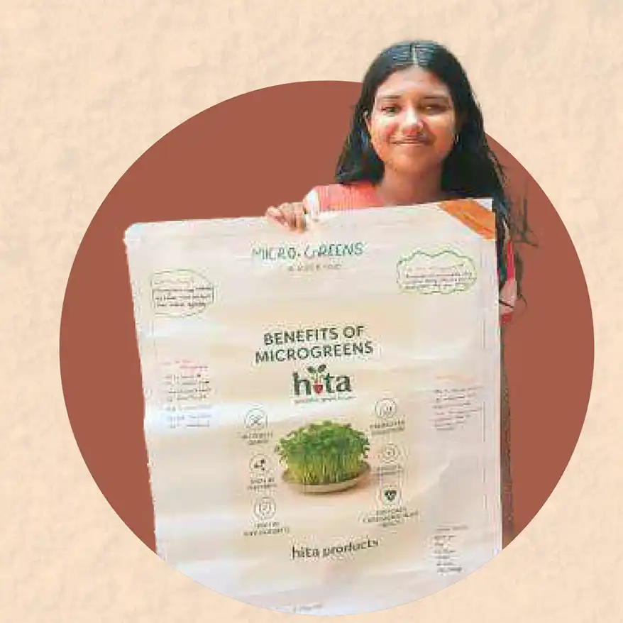 A girl holding a poster that outlines the benefits of microgreens, featuring vibrant graphics and information about health and nutrition.