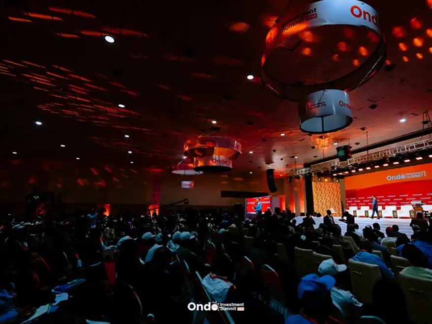A large audience seated in a conference hall during the Ondo Investment Summit, with stage lighting and banners visible.