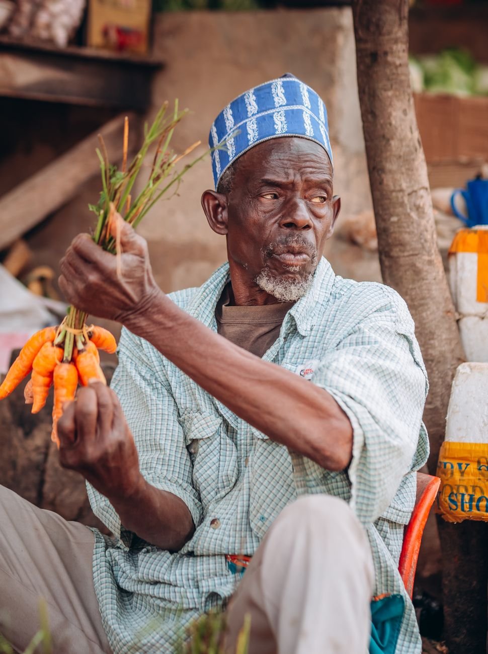 man in hat sitting and holding carrots