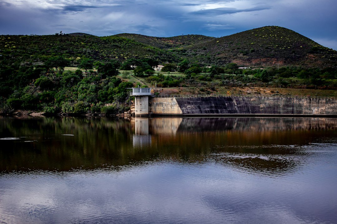 A concrete dam wall reflecting in a calm reservoir lake, South Africa