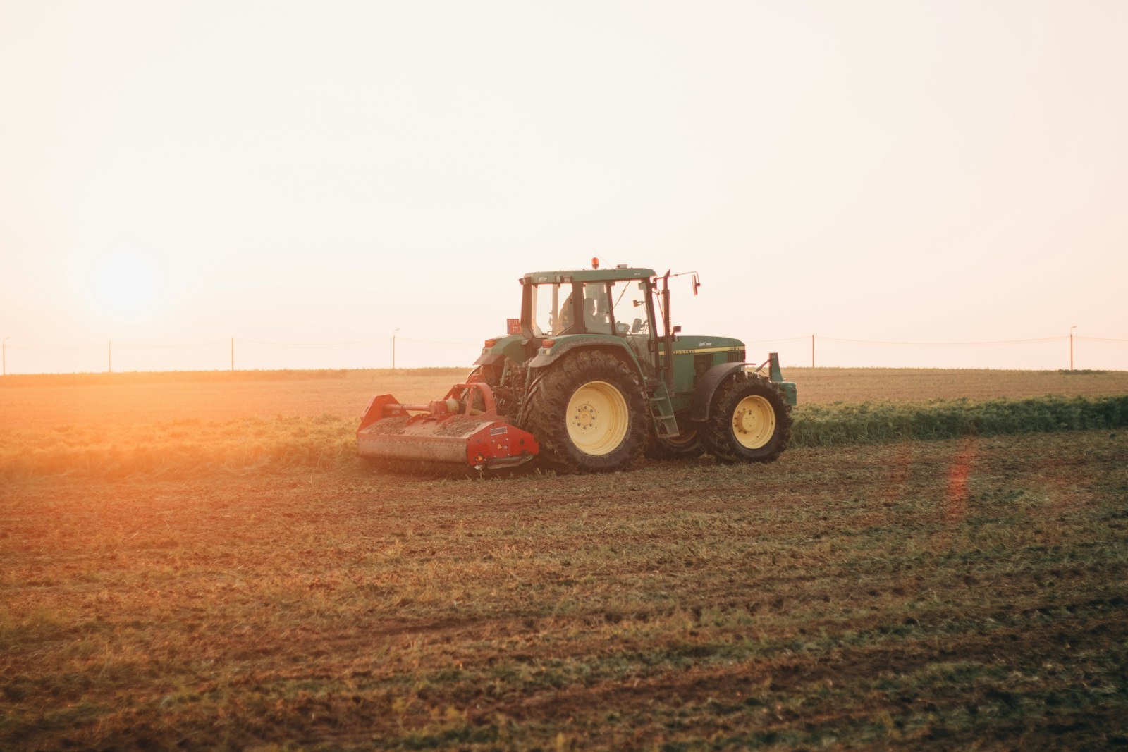 Red tractor working a brown field