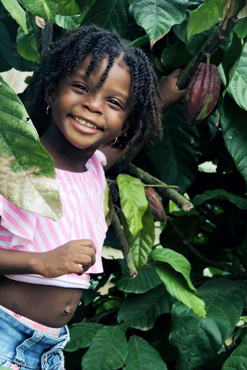 girl smiling under green cacao tree