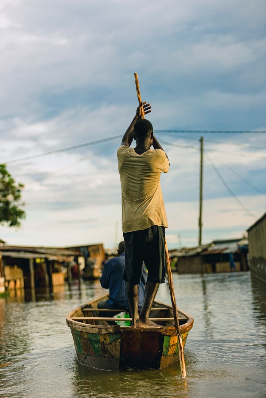 men on boat on water in village during flood