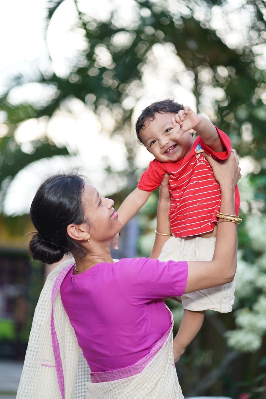 joyful mother lifting happy child outdoors