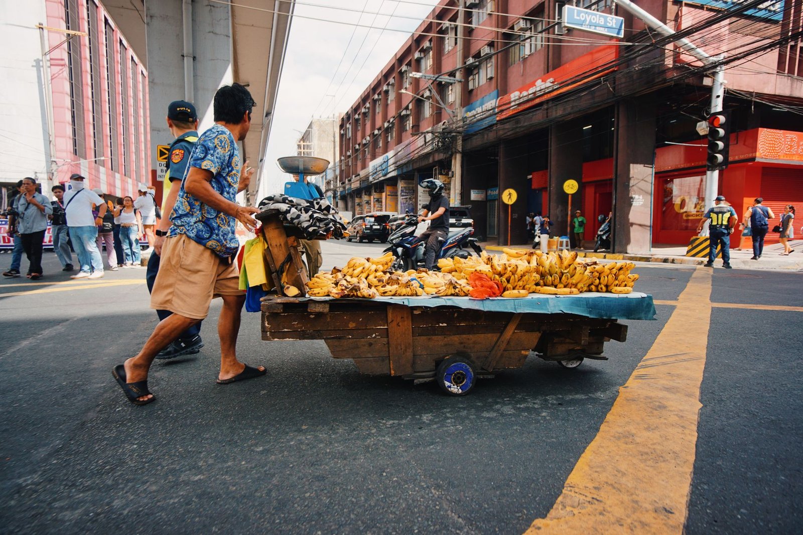 street vendor pushes banana cart in busy urban area
