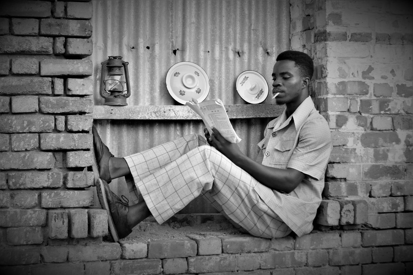 grayscale photo of man smoking and reading