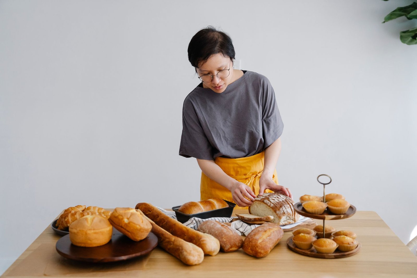 female baker looking at baked breads and pastry