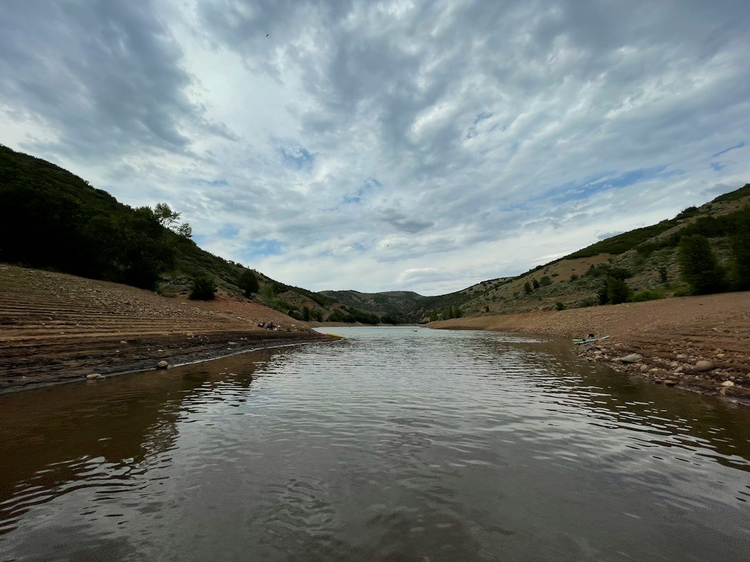 A body of water surrounded by mountains, showing a low reservoir level