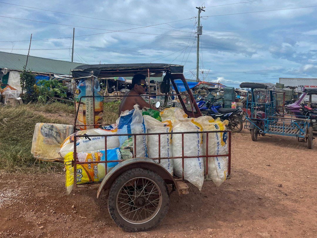 Man driving a three-wheeled vehicle loaded with sacks