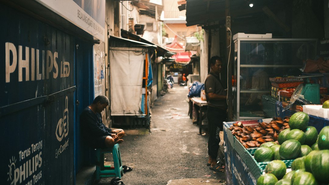 A narrow alleyway market with vendors and produce in Jakarta